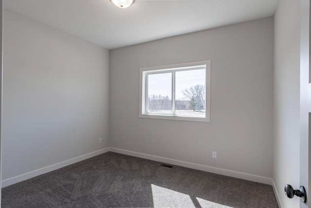 unfurnished room featuring visible vents, dark carpet, and baseboards