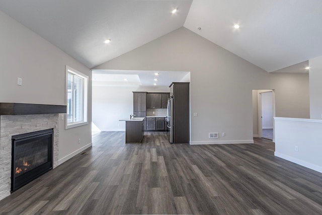 unfurnished living room with baseboards, visible vents, high vaulted ceiling, dark wood finished floors, and a fireplace