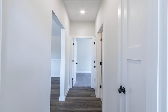 hallway featuring dark wood-type flooring and baseboards