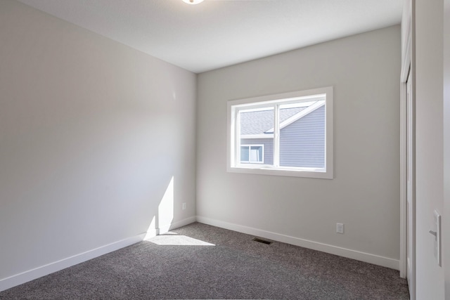 carpeted spare room with visible vents and baseboards