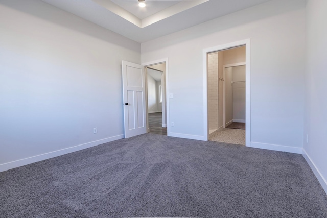 unfurnished bedroom with a tray ceiling, baseboards, and carpet floors