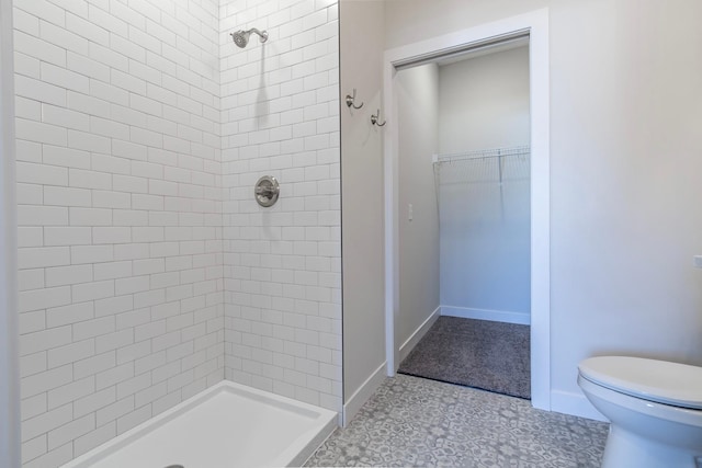 full bathroom featuring a walk in closet, baseboards, toilet, and a stall shower