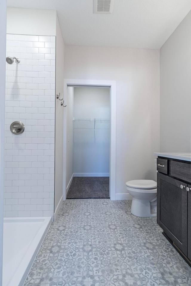 full bathroom with visible vents, a walk in closet, toilet, a stall shower, and baseboards