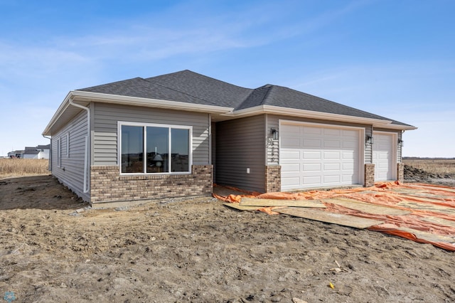 ranch-style house with an attached garage, brick siding, and roof with shingles