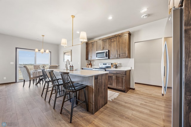 kitchen with a breakfast bar, light countertops, light wood finished floors, and appliances with stainless steel finishes