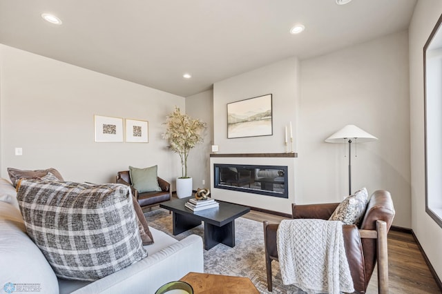 living area featuring a glass covered fireplace, recessed lighting, and wood finished floors