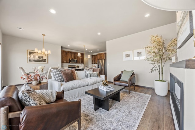 living area featuring recessed lighting, wood-type flooring, a notable chandelier, and a fireplace