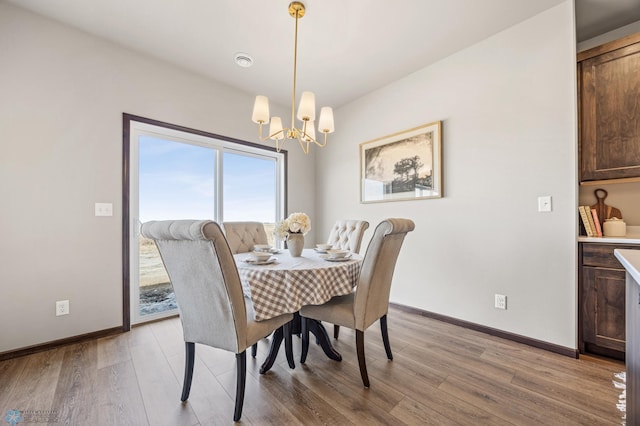 dining room with baseboards, a notable chandelier, and light wood-style flooring