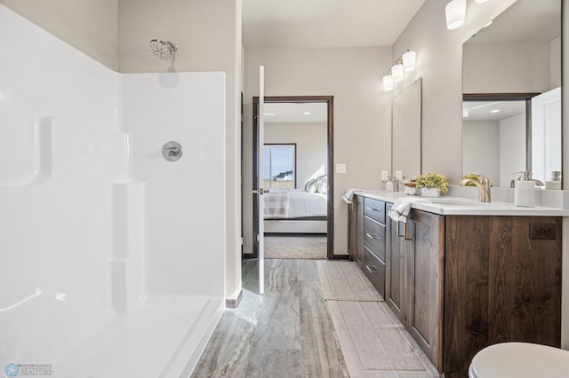 ensuite bathroom with ensuite bath, baseboards, vanity, and walk in shower