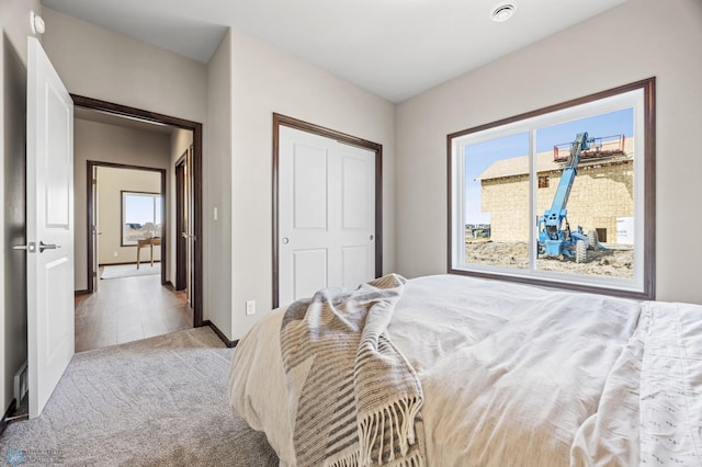 carpeted bedroom with a closet and baseboards