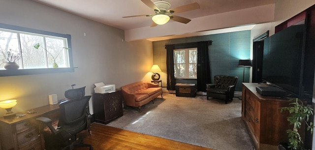 home office with plenty of natural light, a baseboard heating unit, ceiling fan, and wood finished floors