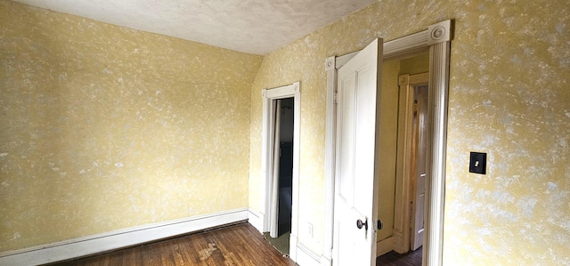 unfurnished room with wallpapered walls, wood finished floors, and baseboard heating