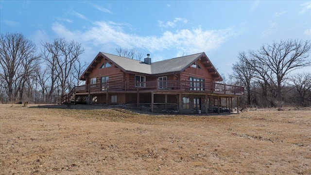 back of property with stairs, a wooden deck, log siding, and a chimney