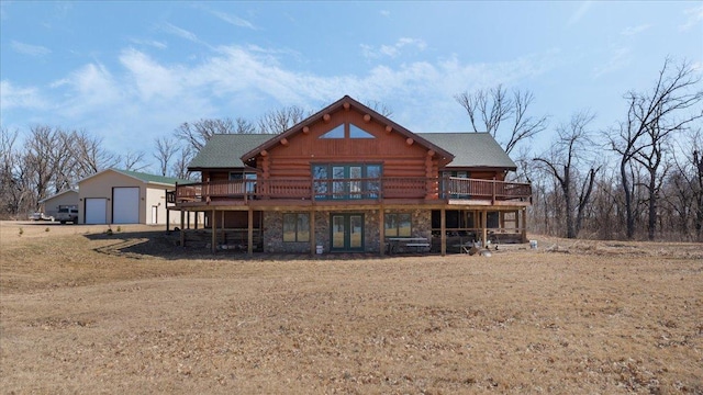 rear view of property featuring log siding, a garage, a deck, an outbuilding, and stone siding