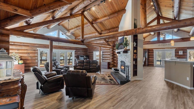 living room with wood finished floors, rail lighting, a fireplace, and a healthy amount of sunlight