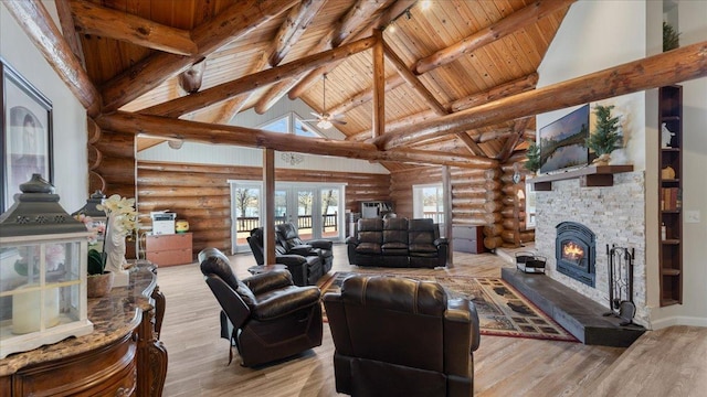 living room with beam ceiling, high vaulted ceiling, wood finished floors, a stone fireplace, and wood ceiling