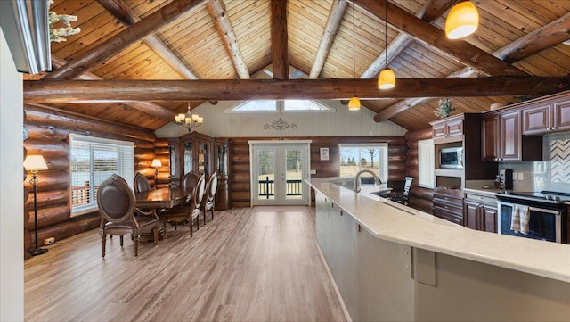 kitchen with beam ceiling, light wood-style flooring, a sink, stainless steel appliances, and french doors