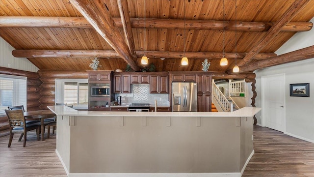 kitchen with lofted ceiling with beams, appliances with stainless steel finishes, dark wood-style flooring, and light countertops