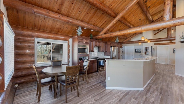 kitchen featuring lofted ceiling with beams, light wood-style floors, appliances with stainless steel finishes, and light countertops