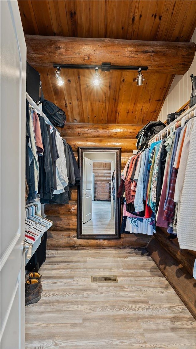 walk in closet with beam ceiling, visible vents, and wood finished floors