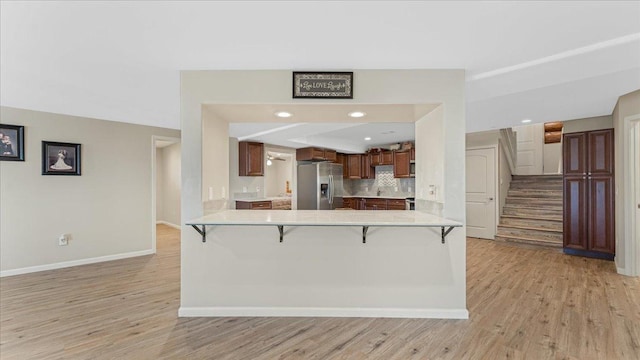 kitchen with a breakfast bar, light countertops, stainless steel fridge, and light wood-type flooring