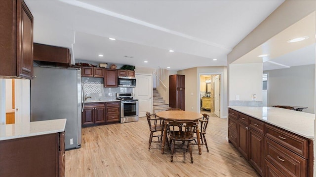 kitchen featuring dark brown cabinetry, decorative backsplash, recessed lighting, light wood-style floors, and stainless steel appliances