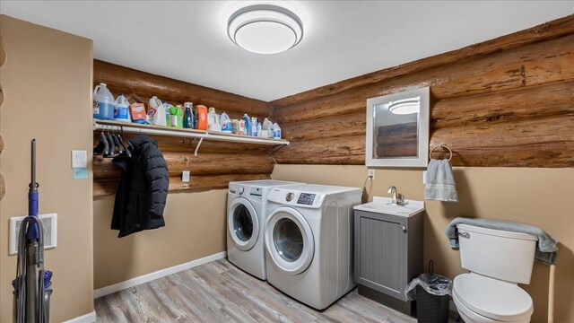 washroom with light wood finished floors, baseboards, laundry area, washer and dryer, and a sink