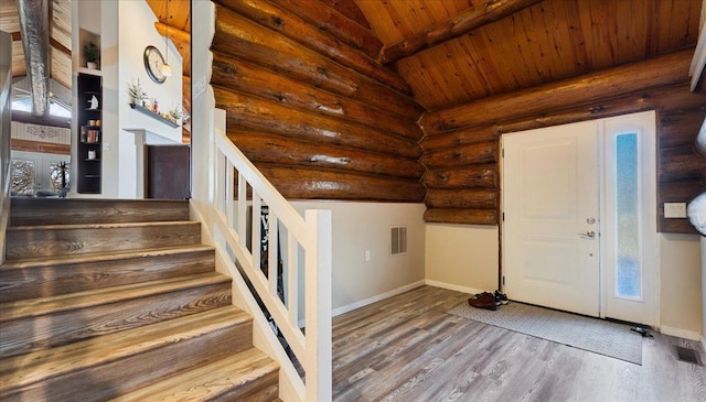 foyer with stairway, wood finished floors, visible vents, log walls, and lofted ceiling with beams