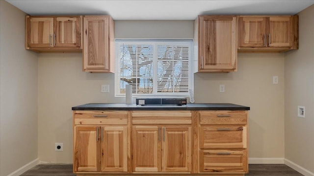 kitchen with light brown cabinets, baseboards, dark countertops, and dark wood-style flooring