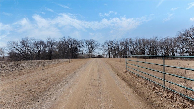 view of road with a gate, a rural view, and dirt driveway