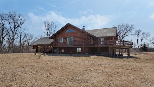 rear view of house featuring log siding, a chimney, a wooden deck, and stairs