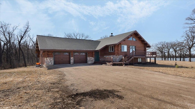 log-style house featuring an attached garage, stone siding, dirt driveway, a deck, and log exterior