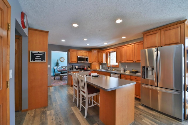 8403 Red Pine Cir, Baxter, MN 56425 - kitchen featuring stainless steel appliances, a textured ceiling, brown cabinetry, recessed lighting, and a kitchen island
