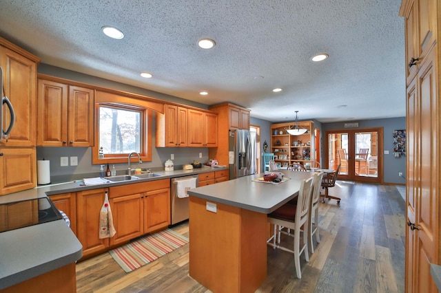8403 Red Pine Cir, Baxter, MN 56425 - kitchen with a sink, appliances with stainless steel finishes, a textured ceiling, a center island, and a breakfast bar area