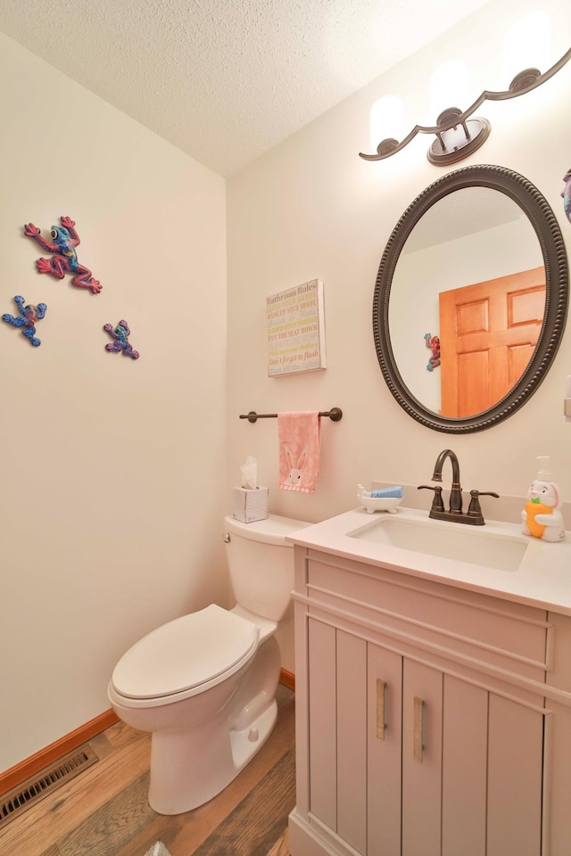 8403 Red Pine Cir, Baxter, MN 56425 - half bathroom with wood finished floors, toilet, vanity, baseboards, and a textured ceiling