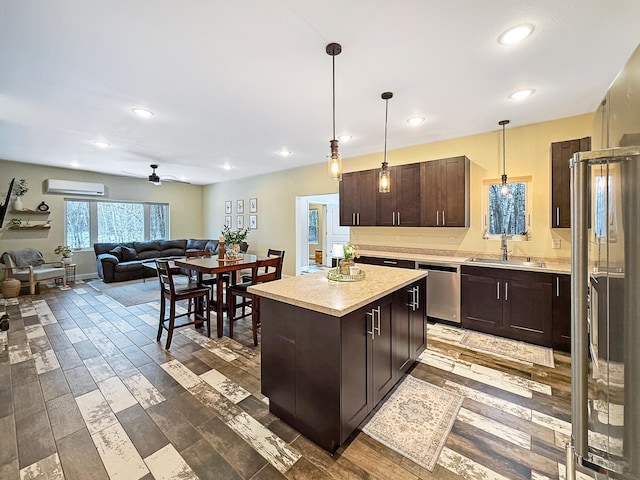 kitchen with dark brown cabinetry, light countertops, a wall unit AC, stainless steel dishwasher, and a sink