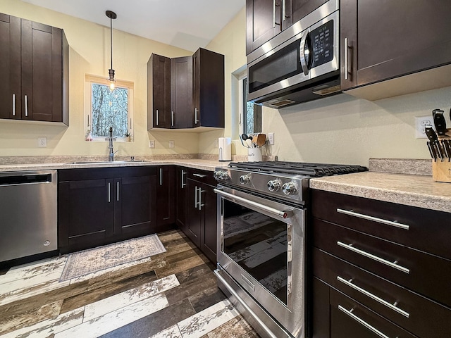 kitchen with a sink, decorative light fixtures, stainless steel appliances, light countertops, and dark brown cabinets