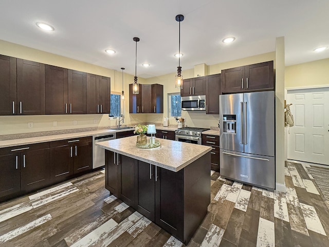 kitchen with a sink, decorative light fixtures, recessed lighting, light countertops, and high end appliances