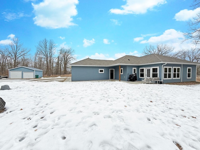 snow covered back of property with a detached garage and an outdoor structure