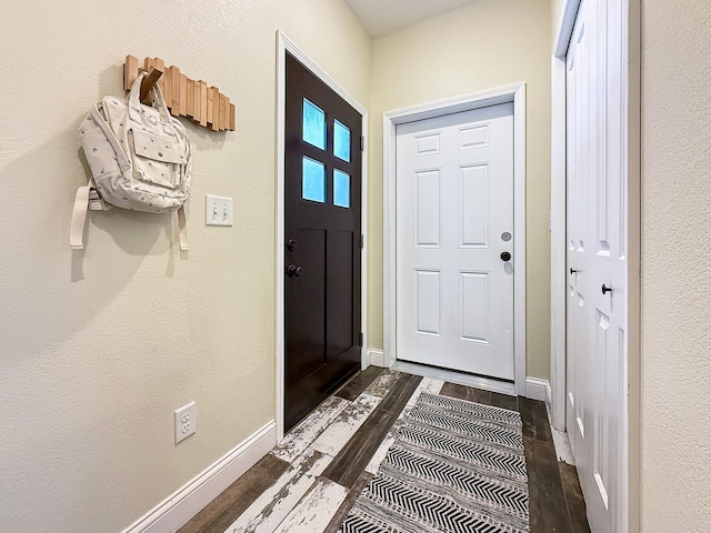 foyer featuring baseboards and dark wood-style flooring