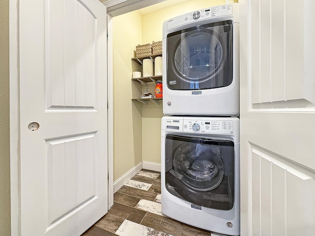 laundry area with dark wood finished floors, laundry area, baseboards, and stacked washer and clothes dryer