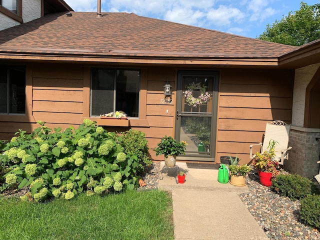 view of exterior entry featuring a shingled roof