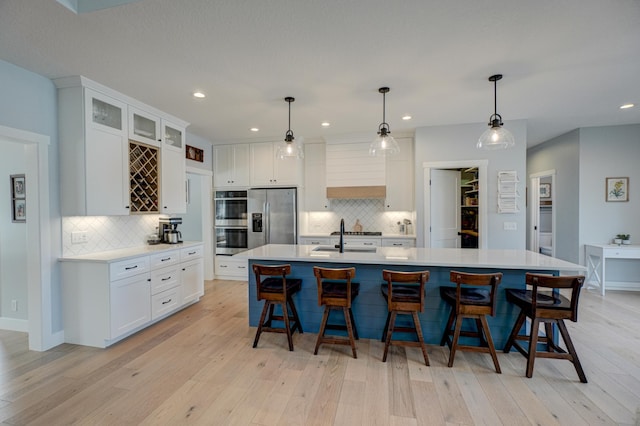 kitchen with light countertops, light wood-style flooring, appliances with stainless steel finishes, and a sink