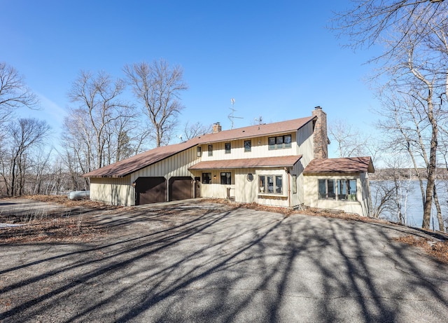 view of front of property with aphalt driveway, an attached garage, and a chimney