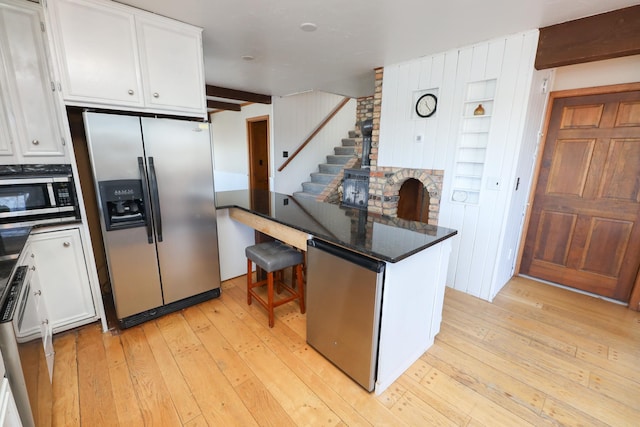 kitchen featuring white cabinetry, dark countertops, appliances with stainless steel finishes, and light wood finished floors