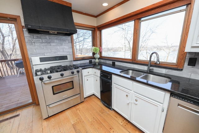 kitchen featuring tasteful backsplash, range hood, stainless steel appliances, white cabinetry, and a sink