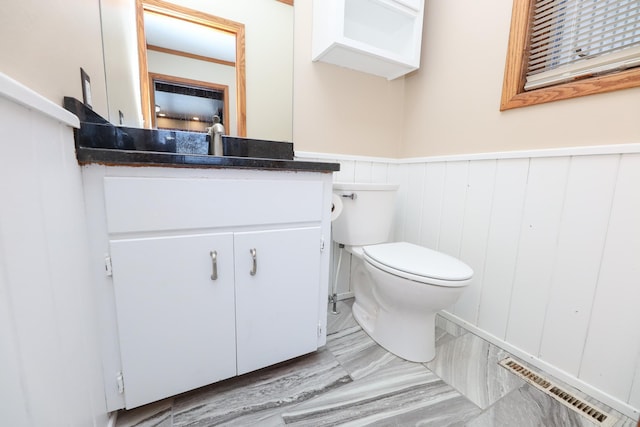 bathroom with vanity, toilet, visible vents, and a wainscoted wall