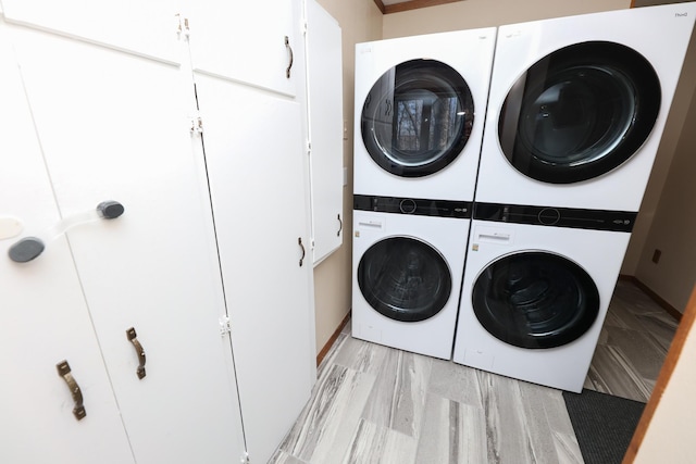 washroom with stacked washer / dryer, cabinet space, and light wood-style flooring