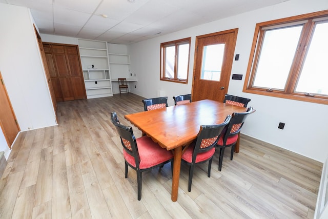 dining space featuring a paneled ceiling and light wood-type flooring