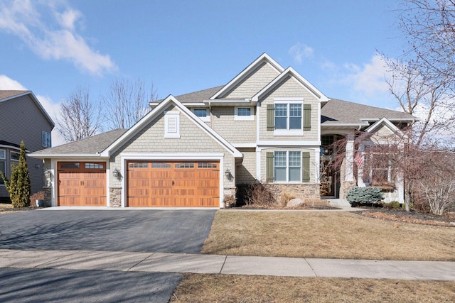 view of front of house featuring aphalt driveway, stone siding, and an attached garage